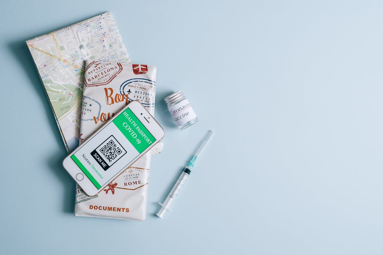 Vaccine and travel documents with COVID-19 health passport on smartphone. Essential travel preparation items.